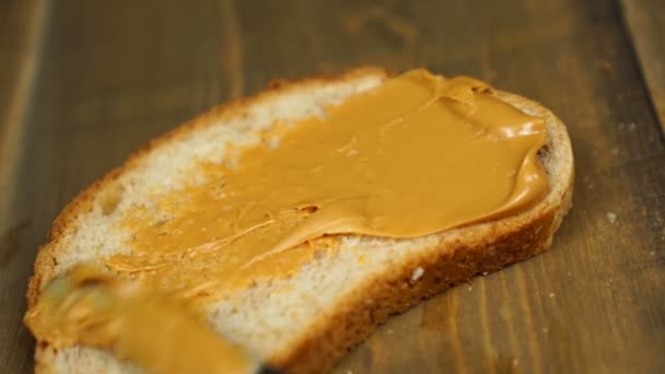 Man makes a peanut butter sandwich. Male hands spreading butter on bread in kitchen — Stock Video