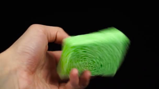 Nova esponja verde na mão do homem na frente do fundo preto — Vídeo de Stock