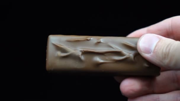 Barra di cioccolato in mano dell'uomo davanti a sfondo nero — Video Stock