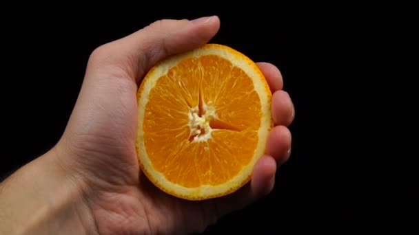 Man holds in his hand half of the cuted yellow orange — Stock Video