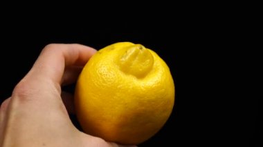 Siyah arka planda bir limon tutan bir erkek.