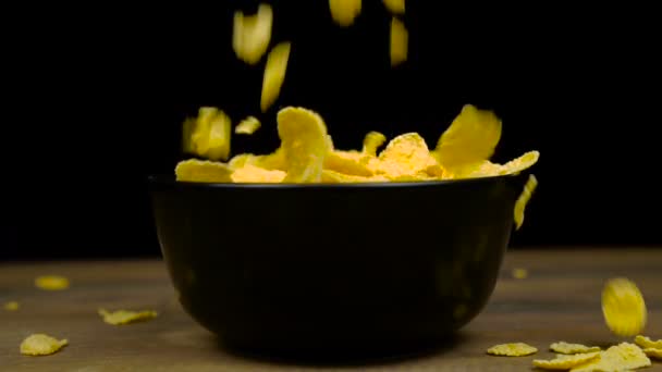 Золотые хлопья кукурузы на завтрак заполнение в миске на деревянный стол, вкусная здоровая пища — стоковое видео