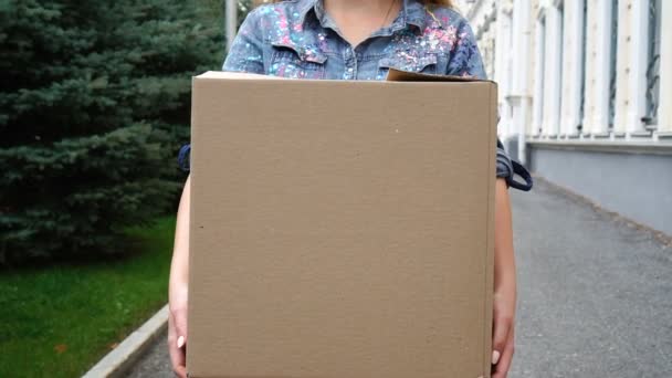 Woman carrying a cardboard box and walking outdoor — Stock Video