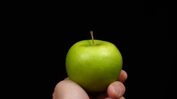 Mano maschile tiene una mela verde su uno sfondo nero — Video Stock
