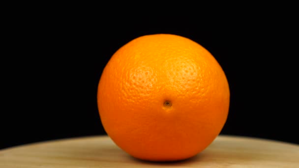 Naranja en una tabla de madera, rotación 360 grados. Fondo negro — Vídeo de stock