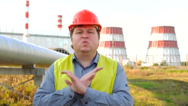 Operaio che mostra stop, respinge gesto, non è d'accordo segno, mani incrociate, in piedi di fronte a una centrale elettrica — Video Stock