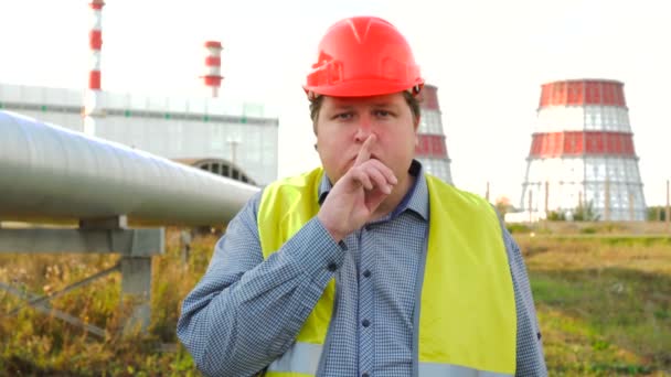 Arbeiter, Ingenieur oder Elektriker schauen in die Kamera und machen Schweigegegeste vor einem Kraftwerk — Stockvideo