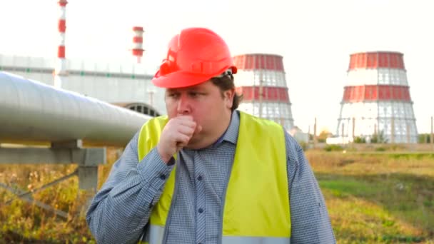 Trabajador, ingeniero o electricista mirando directamente a la cámara tosiendo de pie frente a una central eléctrica — Vídeo de stock