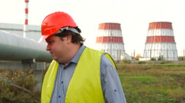İşçi, mühendis ya da elektrikçi doğrudan kameraya bakıyor. Elektrik santralinin önündeki bir arızayı arıyor.