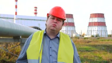 Küstah işçi, mühendis ya da elektrikçi doğrudan kameraya bakıyor ve bir elektrik santralinin önüne tükürüyor.
