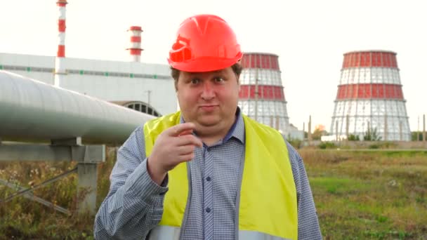 Trabajador, ingeniero o electricista mirando directamente a la cámara invitando a alguien frente a una central eléctrica — Vídeo de stock