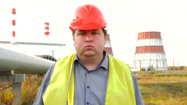 Poważny pracownik, inżynier lub elektryk patrzący bezpośrednio w kamerę stojącą przed elektrownią — Wideo stockowe