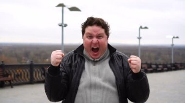 Kameraya bakıp bir şey kazandığını söyleyen mutlu ve şaşırmış şişman adamın portresini yakınlaştır.