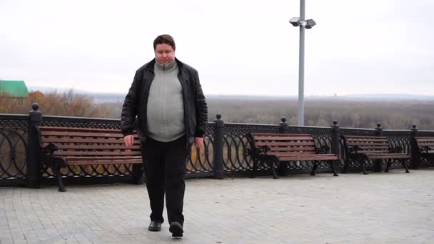 Sebevědomý tlustý muž se dívá na kameru a chodí po městě — Stock video