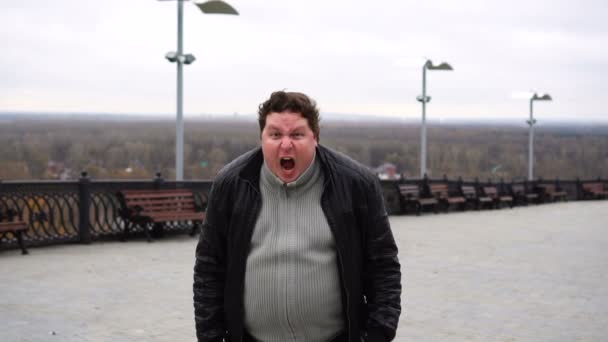 Zoom w portrecie tłustego wściekłego człowieka patrzącego w kamerę i krzyczącego. — Wideo stockowe