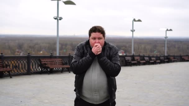 Tlustý muž ve městě cítí chlad, zahřívá ruce během studeného pádu — Stock video