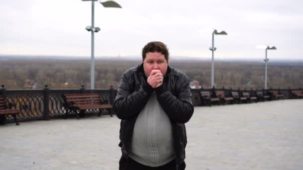 Hombre gordo en la ciudad sintiendo frío, calentando las manos durante el otoño frío — Vídeo de stock