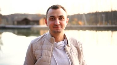 Sonbahar kıyafetleri içinde genç yakışıklı bir adamın portresi. Beyaz sonbahar kıyafetleri giyen bir adam kameraya bakar ve gülümser.