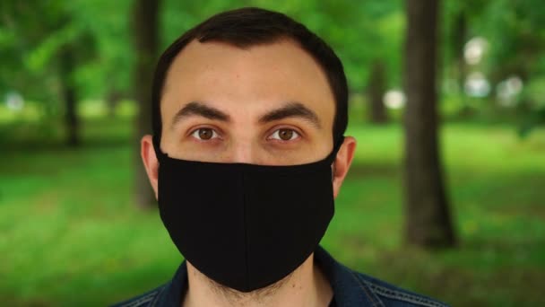 Stilig ung man står utomhus bär medicinsk mask för att skydda andra från virus spridning — Stockvideo