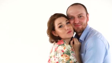 Genç çift birbirine sarılıyor, kameraya gülümsüyor.