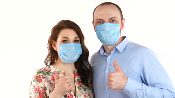 Unga par i skyddande masker håller båda tummarna upp, isolerad på vit bakgrund — Stockvideo