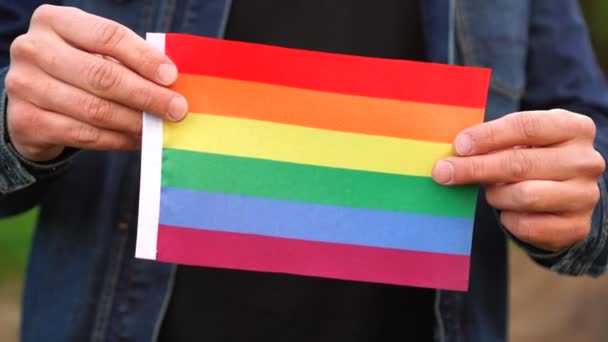 Pria yang memegang bendera LGBT kecil di luar ruangan. konsep liburan — Stok Video