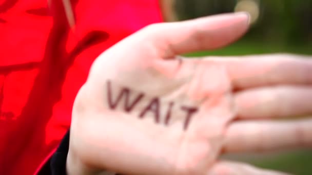 Жінка показує долоні з написом на долоні "Зачекайте " — стокове відео