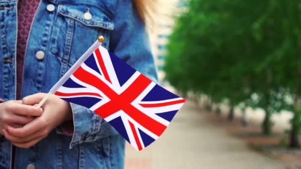 Mouvement lent : Femme méconnaissable tenant le drapeau britannique. Fille marchant dans la rue avec le drapeau national du Royaume-Uni — Video