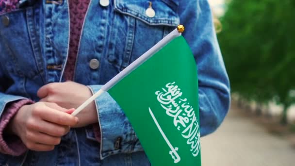 Рух повільний: Невпізнавана жінка тримає саудівський прапор. Дівчина йде по вулиці з національним прапором Саудівської Аравії. — стокове відео