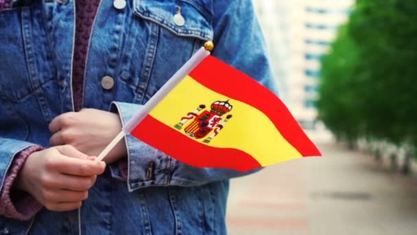 Медленное движение: Неузнаваемая женщина с испанским флагом. Девушка идет по улице с национальным флагом Испании — стоковое видео