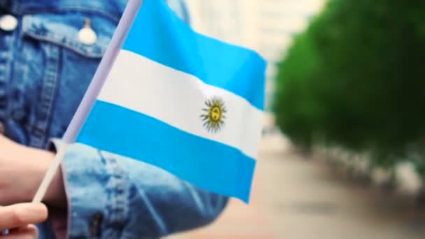 Cámara lenta: Mujer irreconocible con bandera argentina. Chica caminando calle abajo con bandera nacional de Argentina — Vídeos de Stock