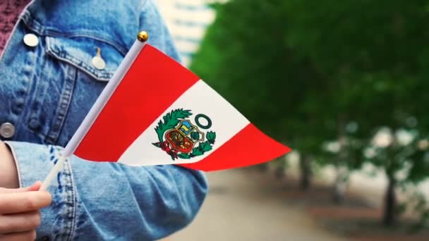 Slow motion: Unrecognizable woman holding Peruvian flag. Girl walking down street with national flag of Peru — Stock Video