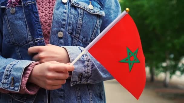 スローモーション:モロッコ国旗を掲揚する認識できない女性。モロッコの国旗を掲げて街を歩く少女. — ストック動画