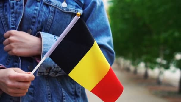 Lambat gerak: dikenali wanita memegang bendera Belgia. Gadis berjalan menyusuri jalan dengan bendera nasional Belgia — Stok Video