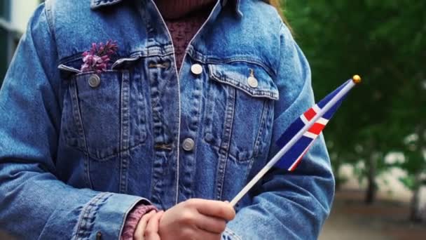 Медленное движение: Неузнаваемая женщина с исландским флагом. Девушка, идущая по улице с государственным флагом Исландии — стоковое видео
