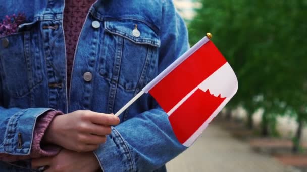 Медленное движение: Неузнаваемая женщина с канадским флагом. Девушка идет по улице с национальным флагом Канады — стоковое видео