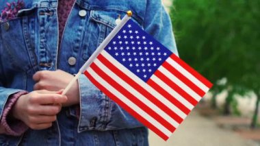 Ağır çekimde, elinde Amerikan bayrağı tutan tanınmayan bir kadın. Amerika Birleşik Devletleri bayrağıyla sokakta yürüyen bir kız.