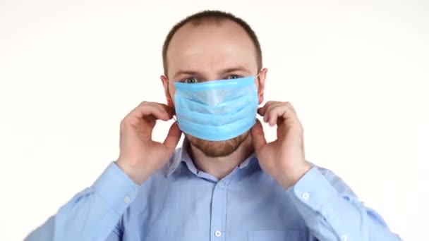 Salgın, beyaz arka planda izole edilmiş koruyucu maske takan genç bir adamın portresi.. — Stok video