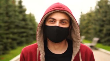Sokakta koruyucu bir tıbbi maske takan kapüşonlu bir gencin portresi. Sağlık ve güvenlik kavramı.