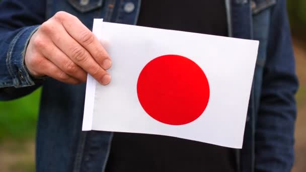 야외에서 일본 국기를 들고 있는 남자. 독립일 또는 국경일 개념 — 비디오