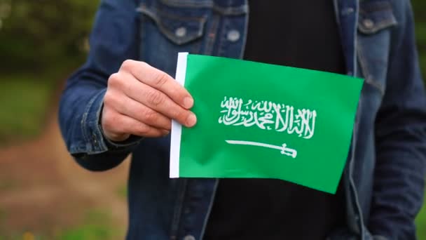 Человек, держащий флаг Саудовской Аравии на улице. День независимости или национальные праздники — стоковое видео