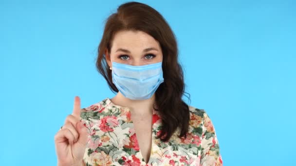 Gyönyörű európai nő orvosi maszkban, aki ujjrázással figyelmeztet a veszélyre.. — Stock videók