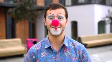 Mutlu pandomimci şapkasını çıkarıp kameraya gülümsüyor.