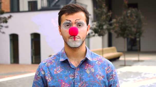 Красивий чоловік клоун дивиться на камеру на відкритому повітрі — стокове відео