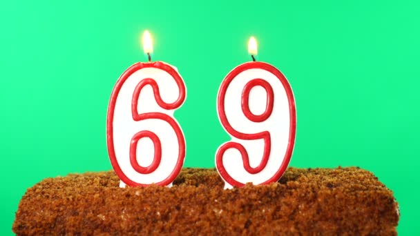 69号的蛋糕点燃了蜡烛。铬键。绿色屏风。被隔离了 — 图库视频影像