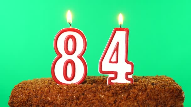 84号的蛋糕点燃了蜡烛。铬键。绿色屏风。被隔离了 — 图库视频影像