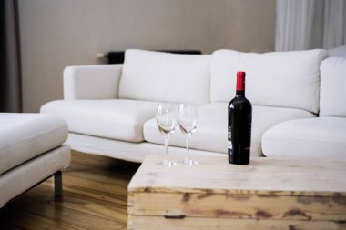 Şişe şarap beyaz kanepe boş oda ahşap tablo.