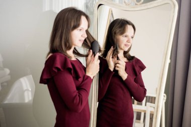 Genç gülümseyen kadın otel odasında ayna önünde.