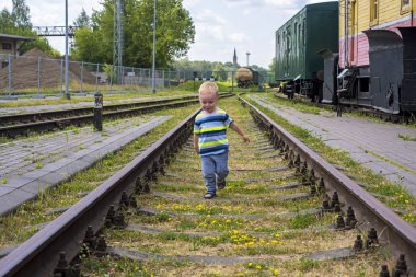 Demiryolu raylar üzerinde küçük bir çocuk. Güneşli yaz gün.