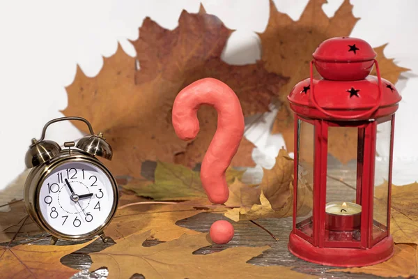 Question sign on autumn leaves background with candle lantern.